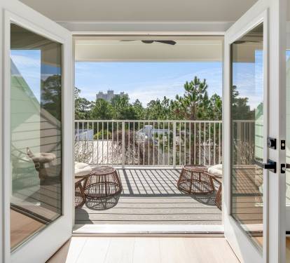 Step onto your private balcony where wicker seating awaits, framing peaceful treetop views and endless sky.