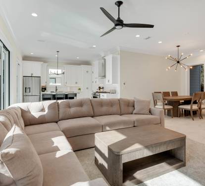 Relax in your spacious open-concept living area with plush sectional seating, modern ceiling fan, and seamless flow to the gourmet kitchen.