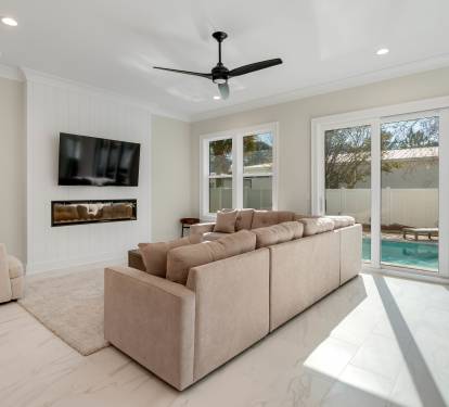 Sink into plush seating while enjoying your private pool view through floor-to-ceiling windows in this bright, modern living space.
