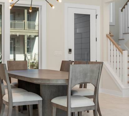 Gather around this elegant dining table for memorable meals, with natural light streaming through windows and a cozy staircase nearby.