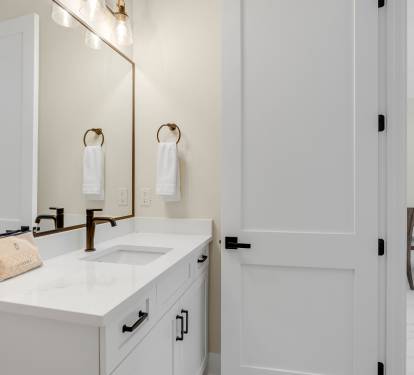 Your pristine bathroom features elegant marble countertops, warm brass fixtures, and fluffy towels waiting for your arrival.