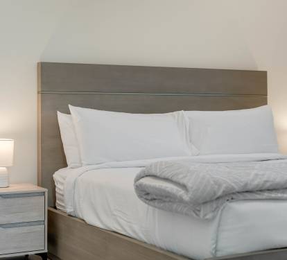 Sink into crisp white linens and plush bedding, where soft lighting creates your perfect retreat for restful nights.