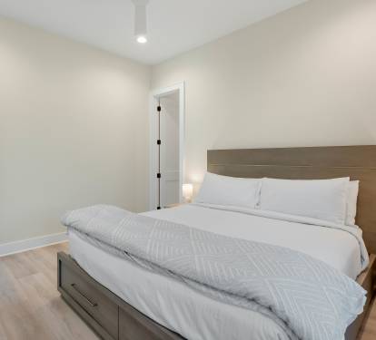 Sink into crisp white linens and wake up refreshed in your peaceful bedroom with modern wood furnishings and soft lighting.