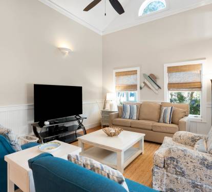Sink into comfort in this bright living room with cozy seating, vaulted ceilings, and natural light streaming through bamboo shades.