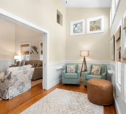 Settle into your cozy reading nook with twin aqua chairs and natural light streaming through windows.