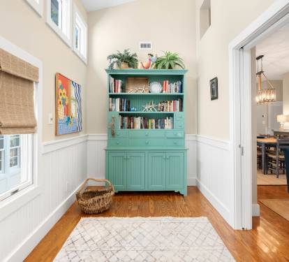 Your private reading nook awaits with turquoise built-ins, natural light, and cozy coastal charm perfect for morning coffee.