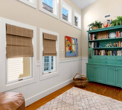 Curl up in your cozy reading nook with rich hardwood floors, charming wainscoting, and a stunning turquoise bookcase filled with stories.