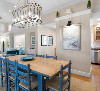 Gather around your beautiful coastal dining table where blue chairs invite memorable meals beneath the statement chandelier.