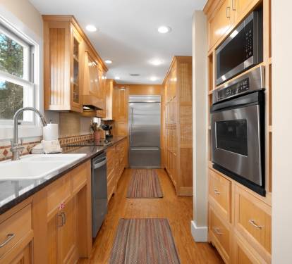 Your gourmet galley kitchen features warm wood cabinetry, granite counters, and premium appliances for memorable home-cooked meals.