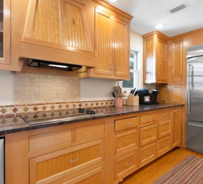 Prepare delicious meals in this elegant kitchen featuring warm wood cabinetry, granite countertops, and modern appliances for your culinary adventures.