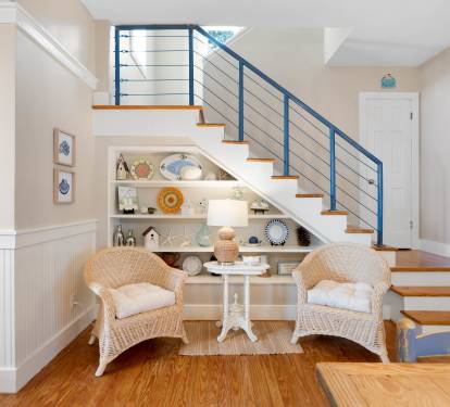 Cozy reading nook beneath the stairs invites you to curl up in wicker chairs with a good book and coastal décor.