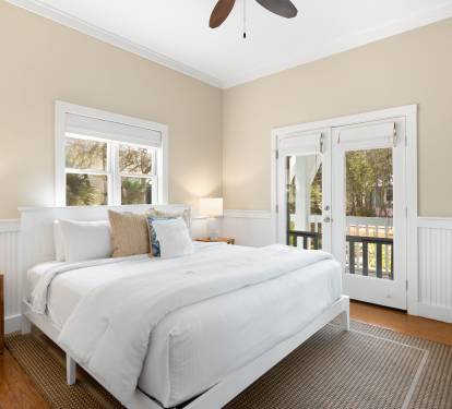 Your peaceful bedroom retreat features crisp linens, warm coastal charm, and French doors opening to your private balcony sanctuary.