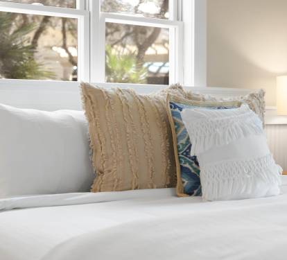 Sink into crisp white linens and plush pillows in your peaceful bedroom retreat, where natural light streams through charming windows.