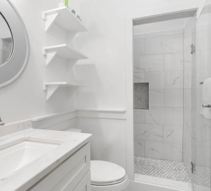 Pristine marble bathroom featuring a luxurious walk-in shower and elegant built-in shelving for your comfort.