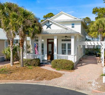 Charming coastal cottage with tropical palm trees and welcoming front porch creates the perfect beachside retreat setting.