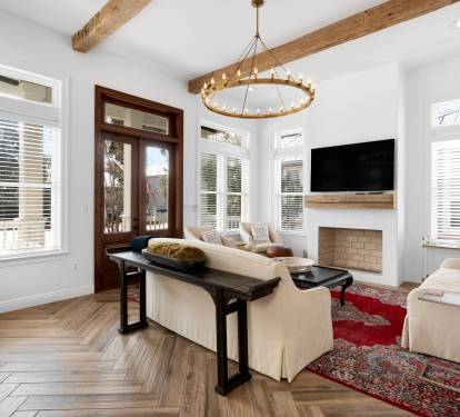 Unwind in your elegant living room featuring soaring wood beams, a cozy fireplace, and abundant natural light streaming through windows.