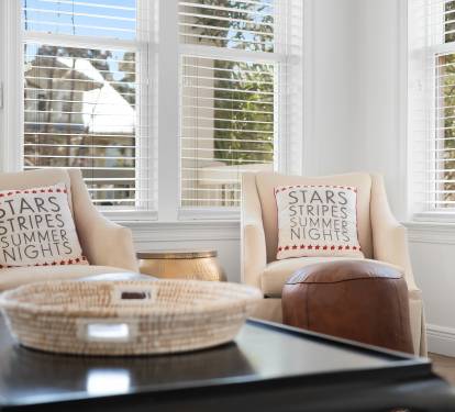 Sink into these cozy chairs by bright windows, where patriotic pillows and warm light create your perfect reading nook.