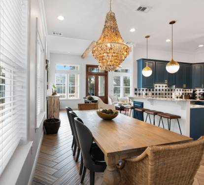 Your open-concept kitchen and dining space gleams with rich navy cabinets, elegant chandeliers, and warm hardwood floors perfect for gathering.