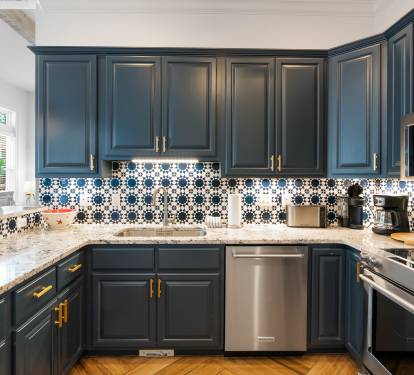 Cook your favorite meals in this stunning kitchen with bold navy cabinets, striking tile backsplash, and premium stainless appliances.