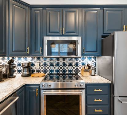 Your stunning kitchen features rich navy cabinets with gold accents and beautiful patterned tile backsplash, perfect for creating memorable meals.