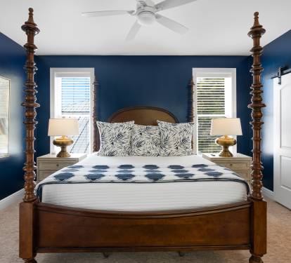 Unwind in your elegant bedroom featuring a stunning four-poster bed, rich navy walls, and coastal artwork that creates a sophisticated coastal retreat.