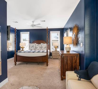 Unwind in your elegant navy sanctuary featuring a four-poster bed and warm wood furnishings for peaceful nights.