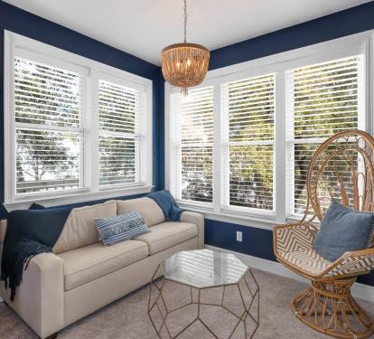 Unwind in your stylish living room with rich navy walls, cozy seating, and a unique wicker peacock chair that's perfect for curling up with a book.