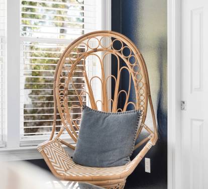 Sink into this cozy peacock chair, where natural light and soft cushions create your perfect reading nook.