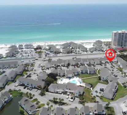 Aerial view of beachfront resort community with pristine white sand beach and emerald waters just steps away from the property.