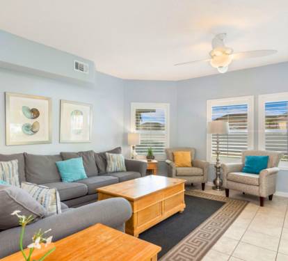 Inviting coastal living room with plush seating, soft natural light, calming beach tones, and a comfortable layout perfect for relaxing after a day at the shore.