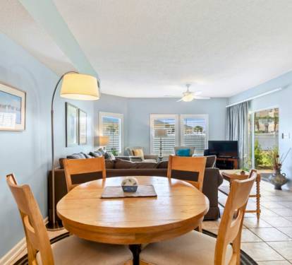 Your bright open-plan living space combines dining and relaxation perfectly, with soothing blue walls and warm wood touches creating a welcoming coastal vibe.