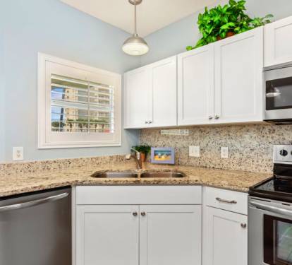 Bright, coastal-style kitchen with granite countertops, white cabinetry, modern appliances, and a clean, open design that makes cooking and gathering easy and enjoyable.