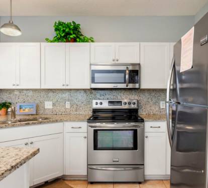 Modern coastal kitchen featuring stainless steel appliances, granite countertops, crisp white cabinetry, and a functional layout designed for easy meal prep and relaxed coastal living.
