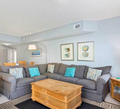 Spacious coastal living area featuring plush sectional seating, soothing beach-inspired décor, and an open layout ideal for gathering, relaxing, and enjoying time together after a day in the sun.