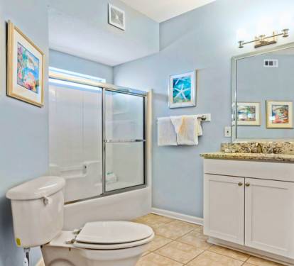 Unwind in your spacious bathroom featuring granite counters, glass shower doors, and cheerful artwork creating a spa-like retreat.