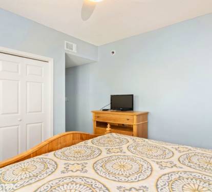 Rest easy in your comfortable bedroom with soft blue walls and warm wood accents creating a peaceful retreat.