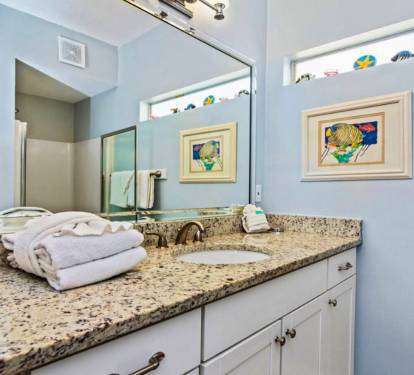 Bright coastal bathroom with granite vanity, double sinks, soft beach décor, and a clean, calming design perfect for refreshing after a day at the beach.