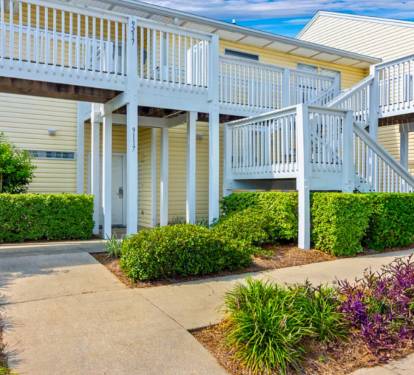 Multi-level vacation rentals with private balconies and lush landscaped grounds create a welcoming coastal retreat atmosphere.