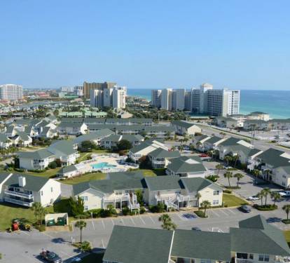 Aerial view of beachfront resort community with distinctive green rooftops and high-rise hotels along the pristine coastline.