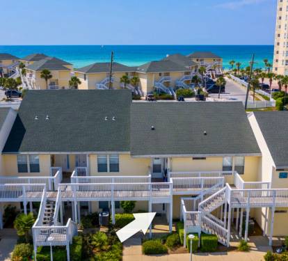 Beach condo situated steps from pristine turquoise waters, surrounded by palm trees and coastal charm in a peaceful resort community.