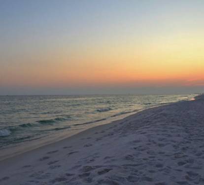 Peaceful Gulf shoreline at sunset, where soft waves meet sugar-white sand and vibrant coastal colors create the perfect backdrop for evening walks and unforgettable beach moments.