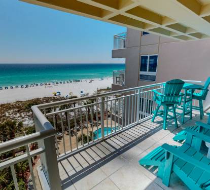 Stunning beachfront balcony with turquoise chairs overlooking pristine white sand and emerald waters. Your perfect retreat awaits.