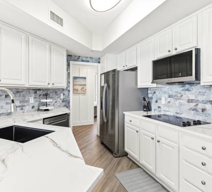 Your fully-equipped kitchen invites culinary adventures with sleek marble counters, stainless appliances, and beautiful coastal-inspired backsplash tiles.