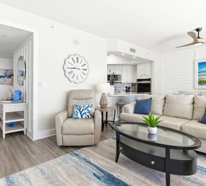 Relax in this coastal-inspired living space with plush seating, ocean artwork, and modern amenities including air conditioning for your comfort.