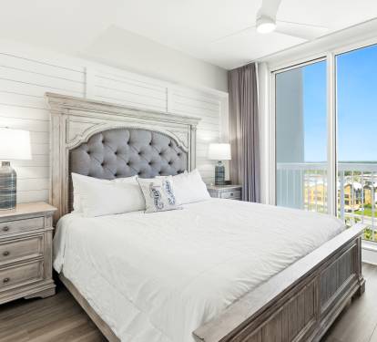 Drift off in your elegant bedroom featuring a plush tufted headboard, crisp white linens, and sweeping balcony views.