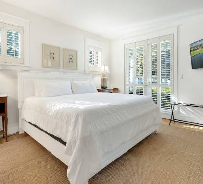 Wake up in your serene bedroom sanctuary, where crisp white linens meet natural light streaming through elegant shutters.