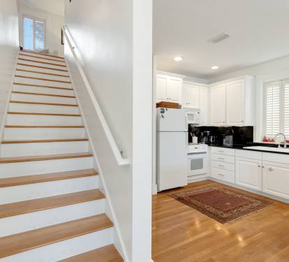 Your bright, modern kitchen flows seamlessly with elegant wooden stairs, creating a welcoming space for cooking and gathering.