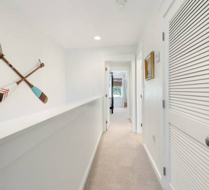 Navigate through this bright hallway where nautical charm meets modern comfort, leading you to your peaceful retreat.