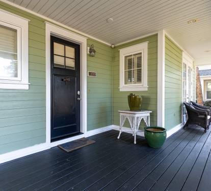 A charming green cottage entrance with dark wood flooring and white accents creates a welcoming arrival at your vacation retreat.