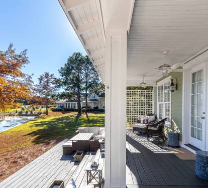 Charming lakeside cottage with covered porch overlooking autumn foliage and waterfront setting.